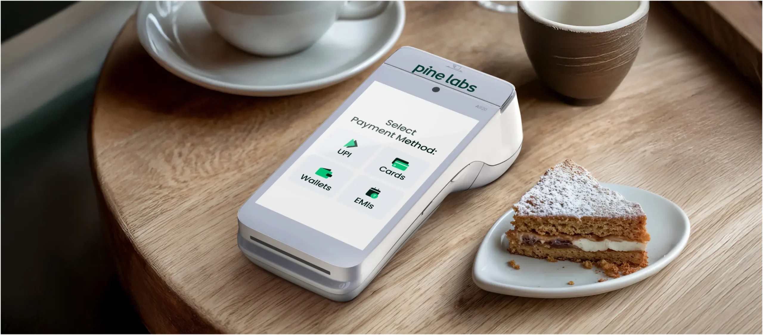 Reliable and Advanced Pine Labs Android PoS Terminal Pine Labs PoS terminal on a table displaying payment method options like UPI, Cards, Wallets, and EMIs