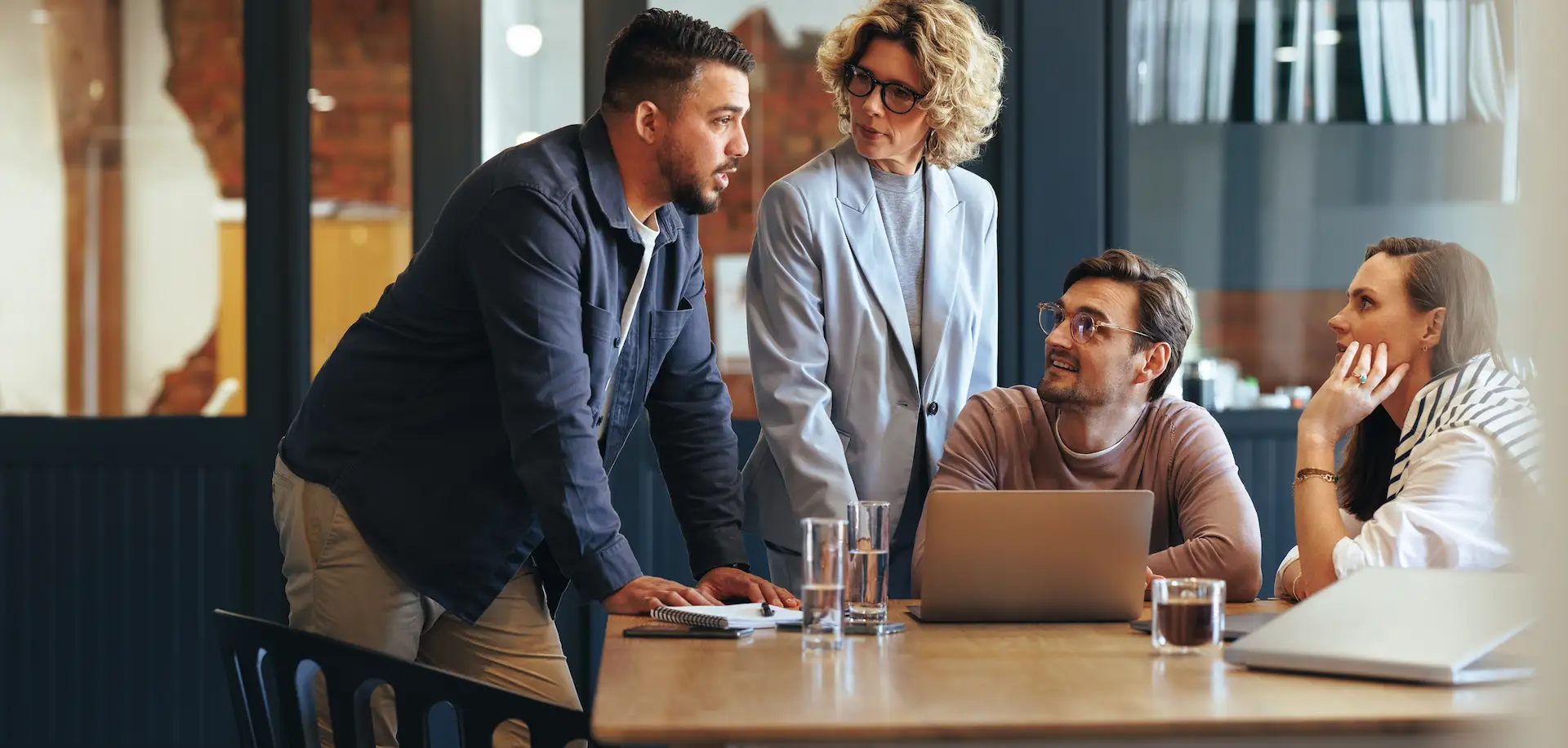 Four colleagues having a discussion around a table with a laptop