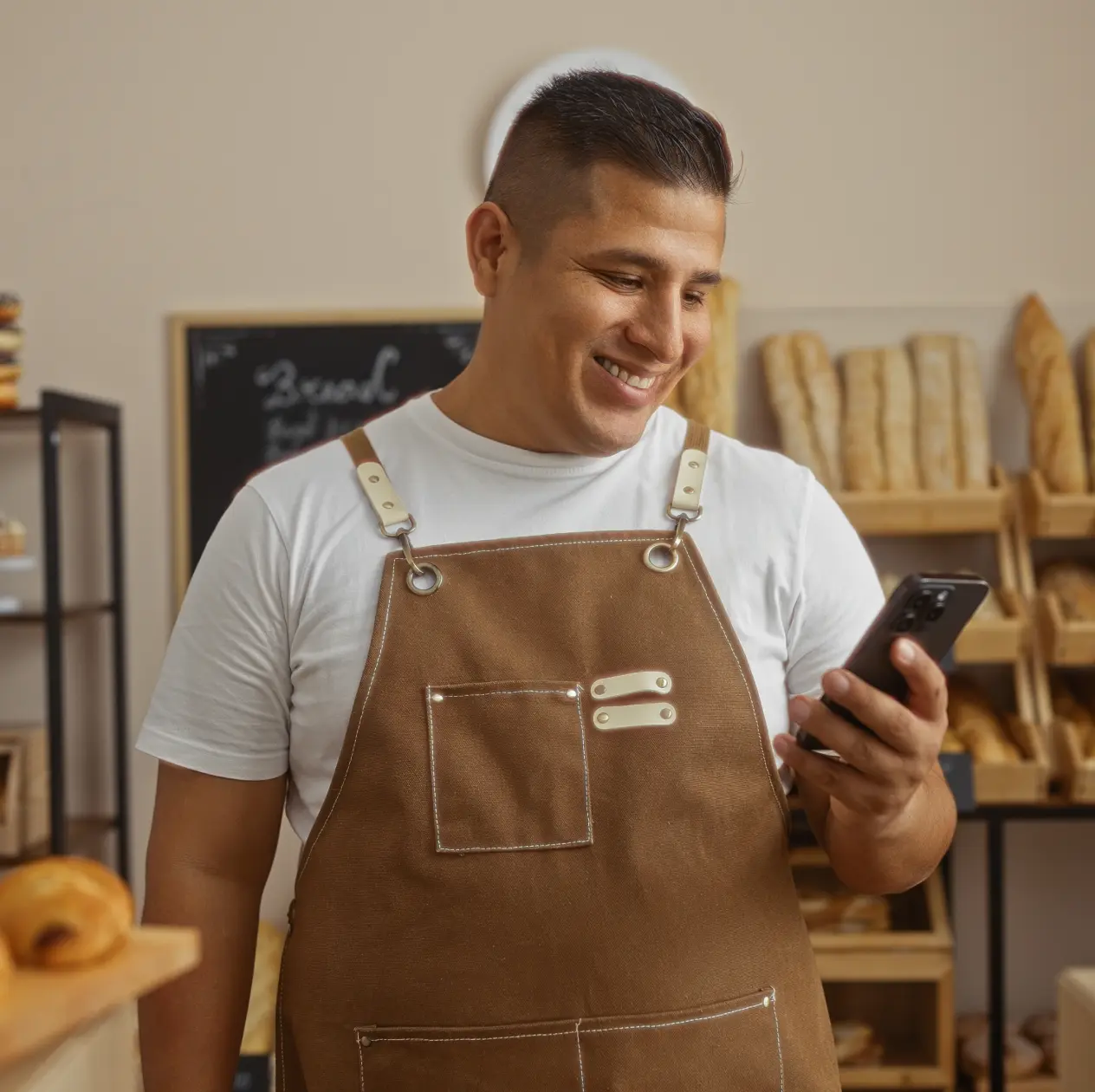 Man in an apron using phone for digital onboarding
