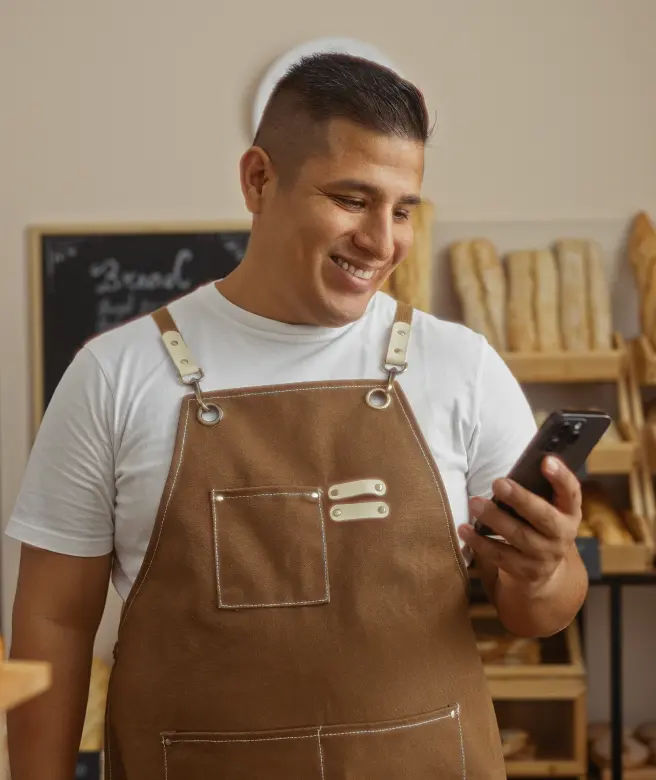 Man in an apron using phone for digital onboarding