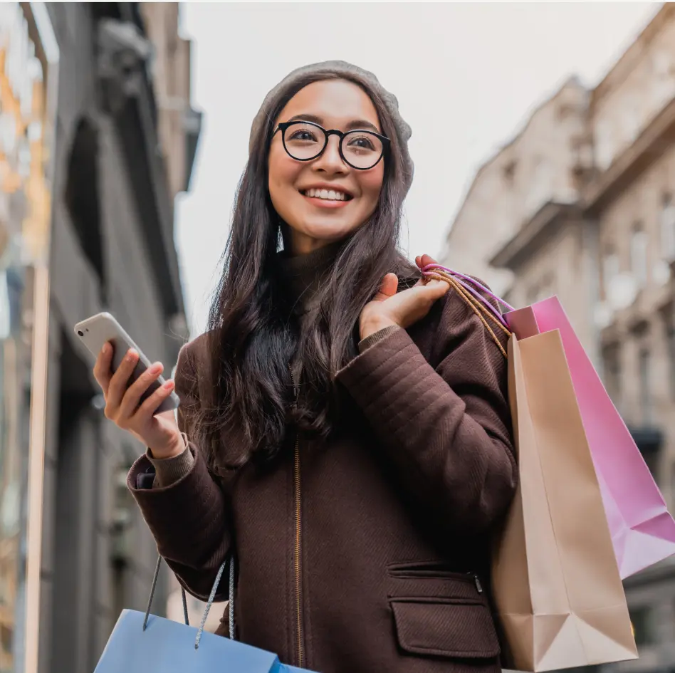 Woman holding shopping bags and phone representing customer acquisition and loyalty benefits