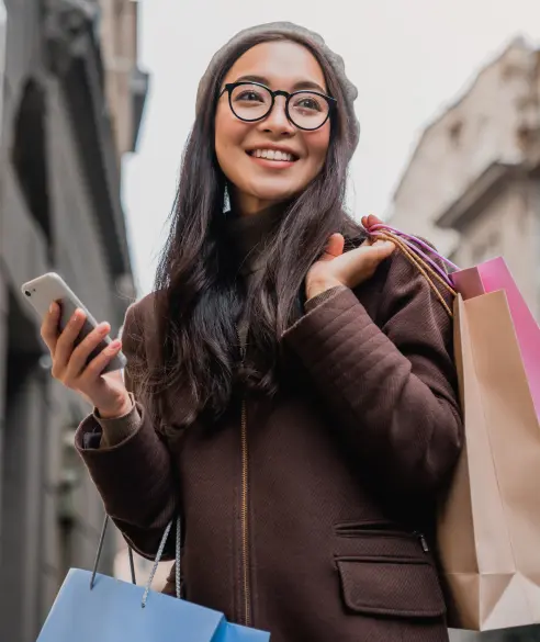Woman holding shopping bags and phone representing customer acquisition and loyalty benefits